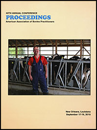 Cover image of the 48th Conference Proceedings: An image of Dr. Fred Gingrich II dressed in a red shirt and overalls and standing in front of dairy cows in a barn interior. Yellow background.
