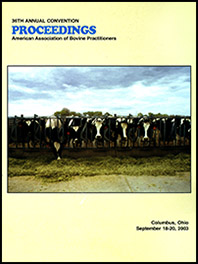 Cover image of the 36th Conference Proceedings: Holstein cows standing in a row at a fence. One cow has put her head through the fence and is curiously inspecting a pile of hay. Yellow background.